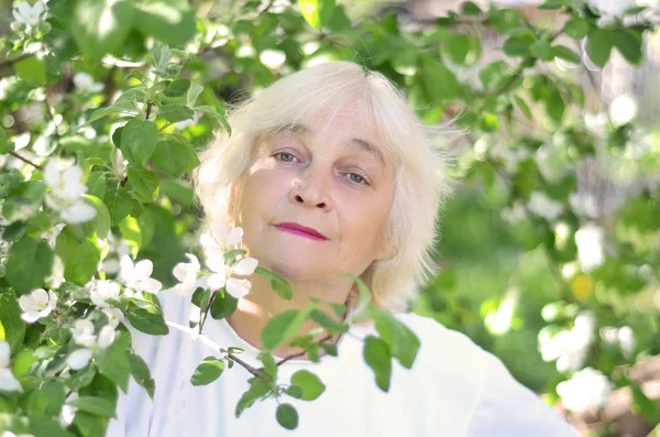 Een bejaarde vrouw in de buurt van de bloeiende boom — Stockfoto