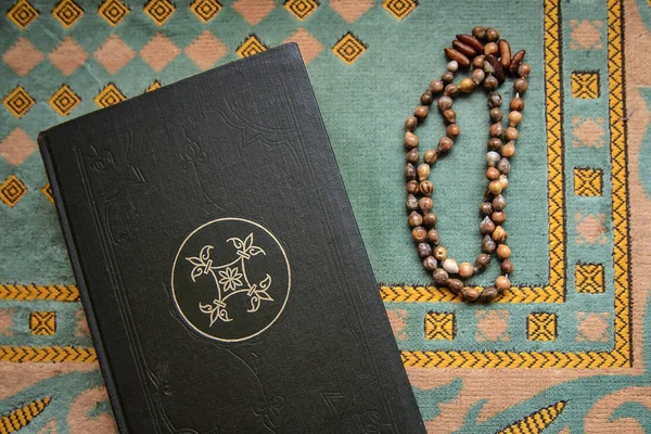 The Koran and the old rosary on a green mat