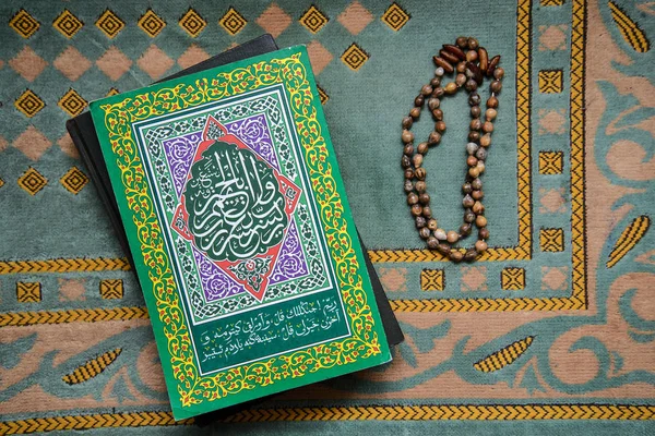 De Koran en de oude rozenkrans op een groene mat — Stockfoto
