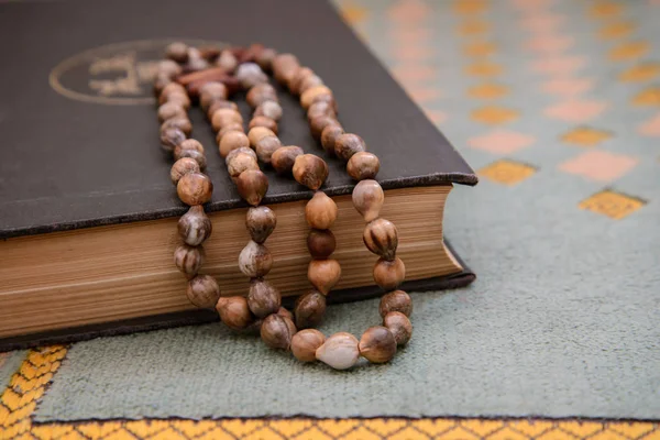 De Koran en de oude rozenkrans op een groene mat — Stockfoto