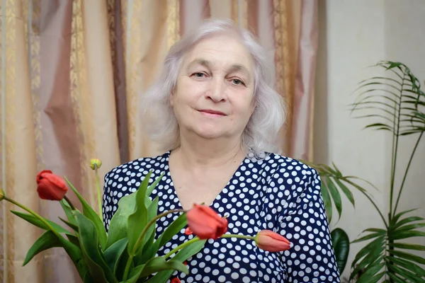 Een oudere vrouw met tulpen — Stockfoto