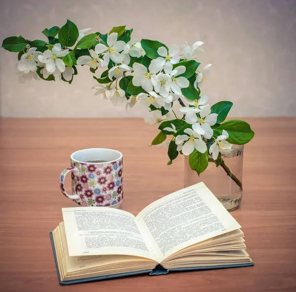 Otwartą książkę na stole z oddziału kwiaty jabłko i filiżankę herbaty — Zdjęcie stockowe