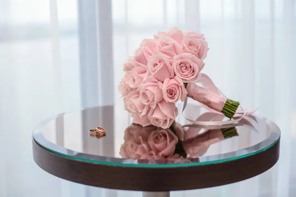 Wedding rings on the table with a bouquet