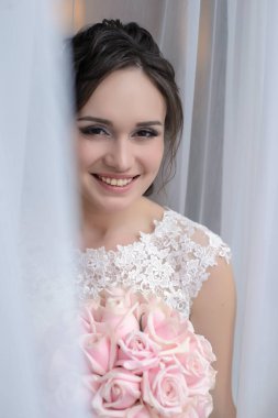 Penceredeki bir buket pembe Gül ve gülümsüyor duran güzel gelin