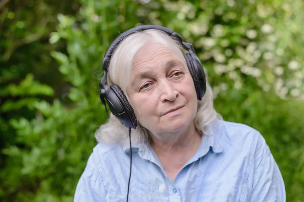 Bejaarde vrouw luisteren naar muziek op koptelefoon — Stockfoto