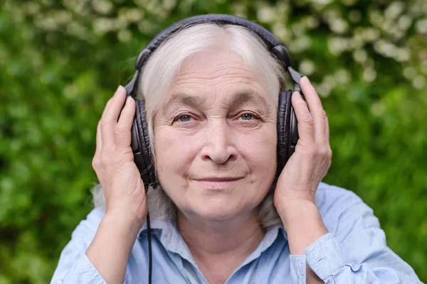 Bejaarde vrouw luisteren naar muziek op koptelefoon — Stockfoto