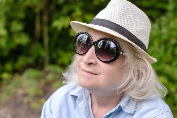 Bejaarde vrouw in hoed en zonnebril — Stockfoto