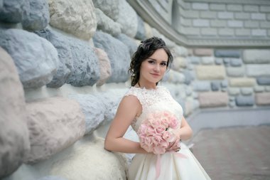 Güzel gelin duvara bir buket ile ayakta