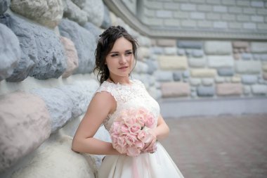 Güzel gelin duvara bir buket ile ayakta