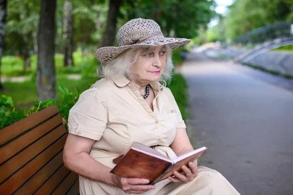 Een oudere vrouw leest een boek in het park — Stockfoto