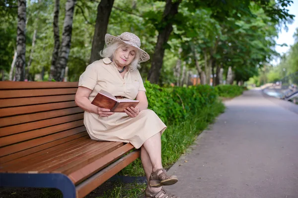 Yaşlı bir kadın parkta bir kitap okur