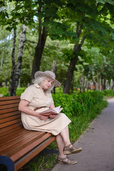 An elderly woman reads a book in the park Stock Photo