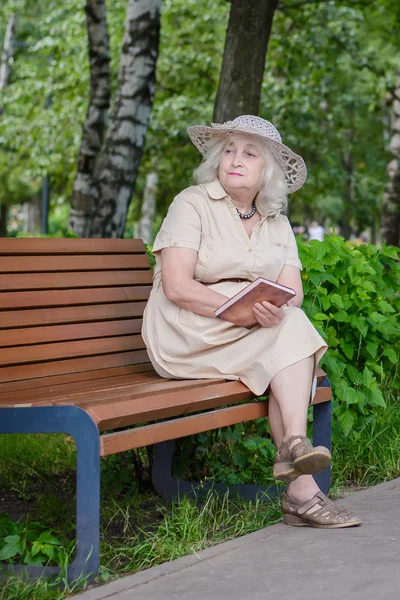 Een oudere vrouw leest een boek in het park — Stockfoto