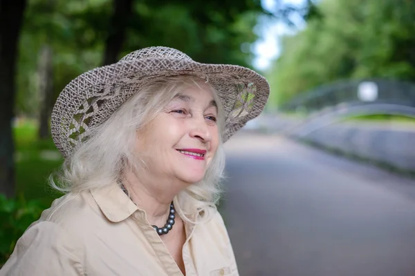Een bejaarde vrouw in het park glimlachen — Stockfoto