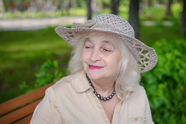 Een bejaarde vrouw in het park glimlachen — Stockfoto