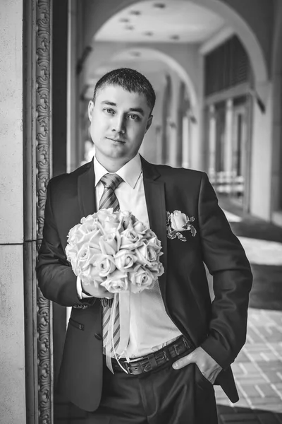 Black and white portrait of the groom with a bouquet of flowers — Stock Photo, Image
