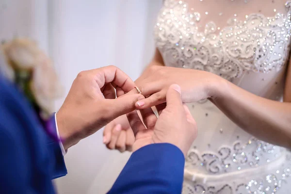 The groom places the wedding ring on the bride\'s finger