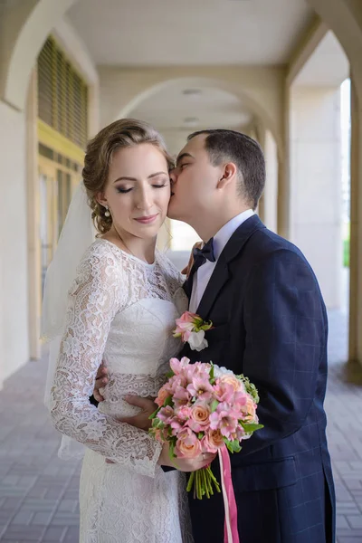 The groom kisses the bride in the arched gallery — Stock Photo, Image