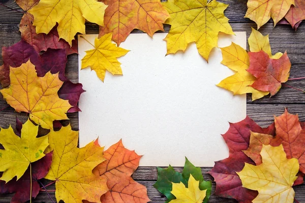 Çerçeve sonbahar yaprakları ve ahşap tahta arka plan üzerinde beyaz kağıdın — Stok fotoğraf
