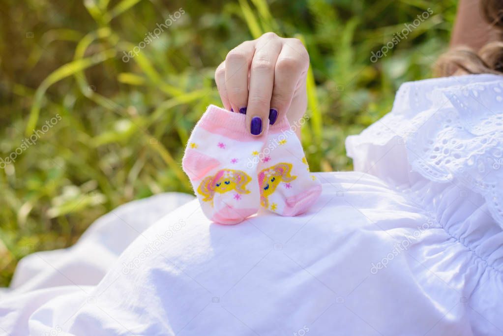 Pregnant woman holding baby socks near the tummy
