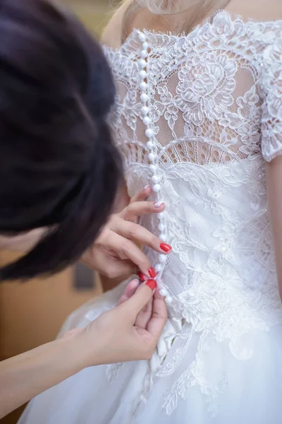 Женские руки застегивают платье подружки невесты на маленькие пуговицы — стоковое фото