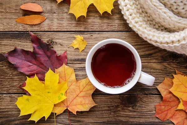 Jesienny obraz żółte listowie, herbatę, szalik i kawałek papieru z piórem na podłoże drewniane — Zdjęcie stockowe