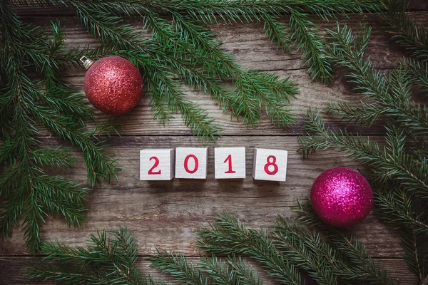 L'immagine con rami di albero di Natale, blocchi con il numero 2018 e palline rosse giocattolo — Foto Stock