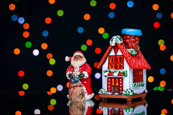 Vánoční obrázek s Santa a dům na pozadí barevných světel — Stock fotografie