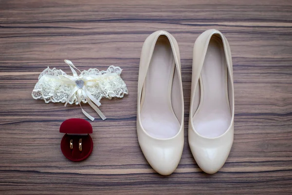 Scarpe da sposa, giarrettiera nuziale e fede nuziale in una scatola su sfondo di legno — Foto Stock