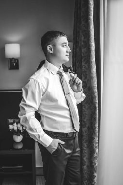 Genç bir adam pencerenin kenarında duruyor