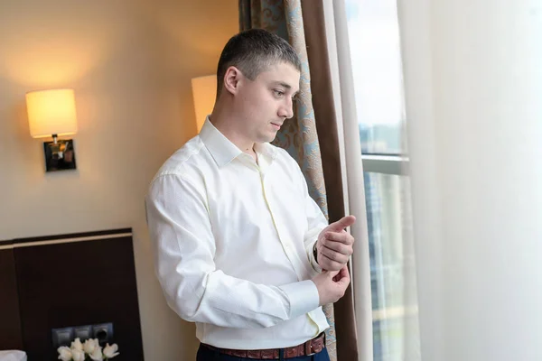 Молодой человек прикрепляет пуговицы к рукавам окна — стоковое фото