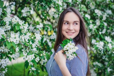 İlkbaharda çiçek açan elma ağaçlarının yakınındaki güzel genç kız