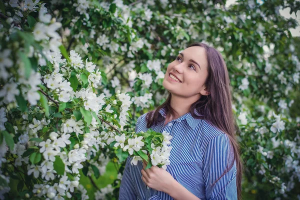 Vacker flicka nära blommande äppelträd under våren — Stockfoto