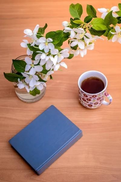 Buch, Tasse mit Tee und einem Zweig eines blühenden Apfelbaums im Frühling — Stockfoto