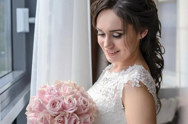 Affascinante sposa alla finestra con un bouquet da sposa — Foto Stock