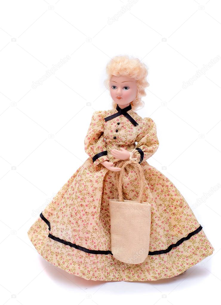 Porcelain doll in a long vintage beige dress with a bag