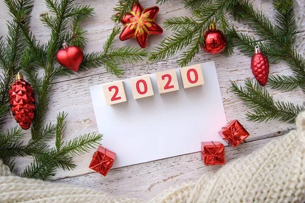 2020 yılbaşı ağacı dalları ve ahşap arka planda kırmızı oyuncaklar