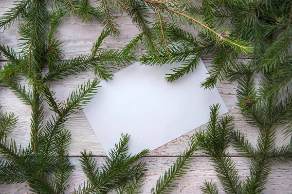 Ram av julgran grenar och ett pappersark på en vit trä bakgrund — Stockfoto