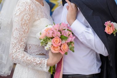 Gelin ve damat düğün buketini yakın tutuyorlar.