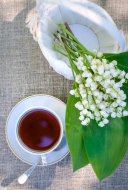 Beyaz bir sepet ve bir fincan çayla vadinin nilüferlerinden oluşan bahar çiçeği.