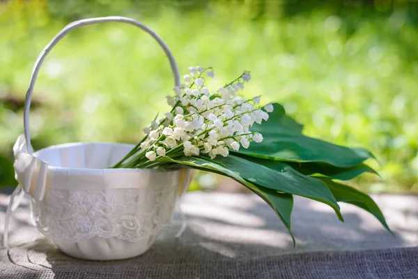 Frühlingsstrauß der Maiglöckchen in einem weißen Korb — Stockfoto