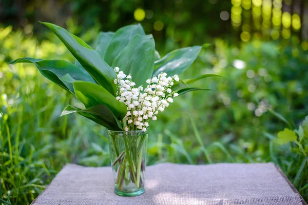 Buquê de flores frescas primavera de lírios brancos do vale em uma mesa no jardim — Fotografia de Stock