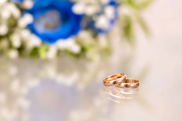 Золотые Обручальные Кольца Рядом Букетом Синих Роз Невесты Стеклянной Поверхности — стоковое фото