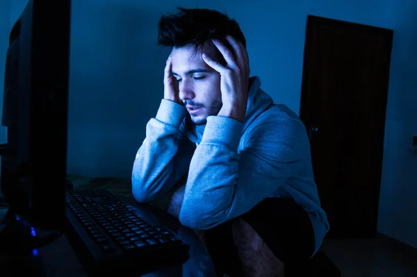 Homem estressado com a cabeça nas mãos perto do computador — Fotografia de Stock