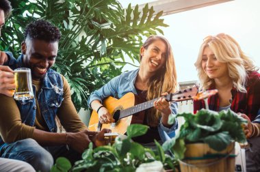 Bir grup çok ırklı arkadaş gitar içerek eğleniyor. 