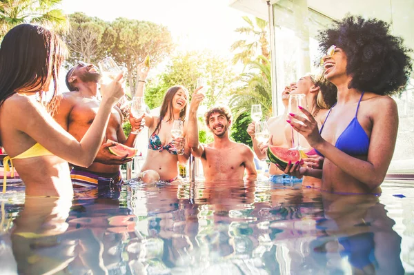 Multi-ethnic group of friends toasting champagne on a pool party
