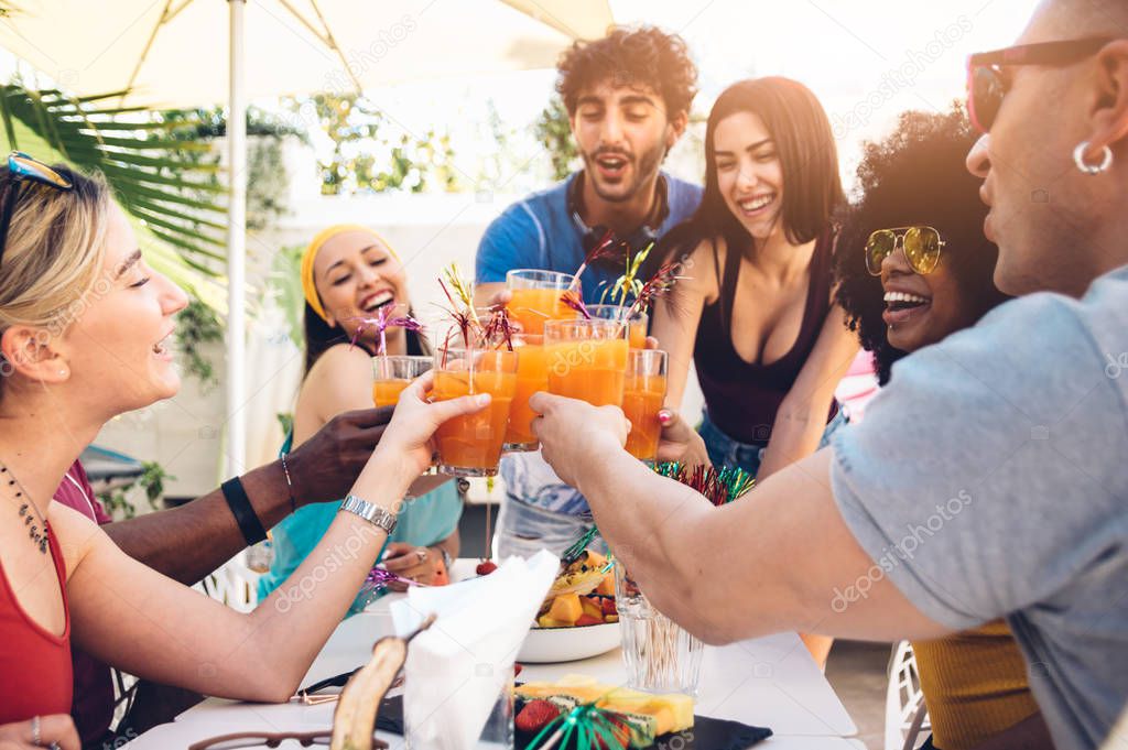 Young multiracial friends toasting beer at barbecue garden party