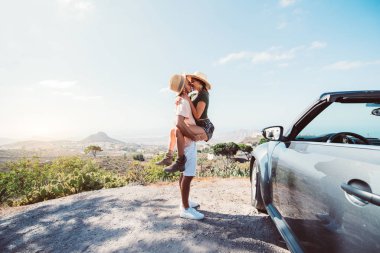 Tenerife 'de romantik bir kaçış. Bir çift, üstü açık bir arabayla uçurumda öpüşüyor.