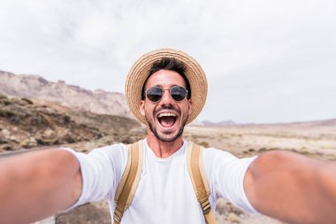 Yakışıklı bir yürüyüşçü, akıllı telefonunu kullanarak dağ yürüyüşü yapıyor.