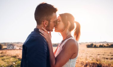 Gün batımında dışarıda öpüşen romantik bir çift..